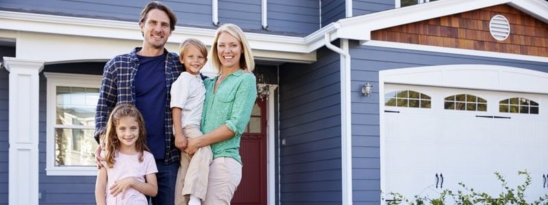 Happy family standing in front of their home with its new roof