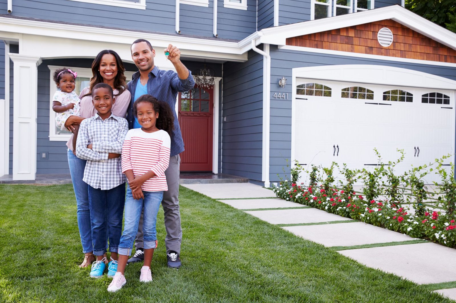 Happy homeowners in front of their house after a successful roof claim